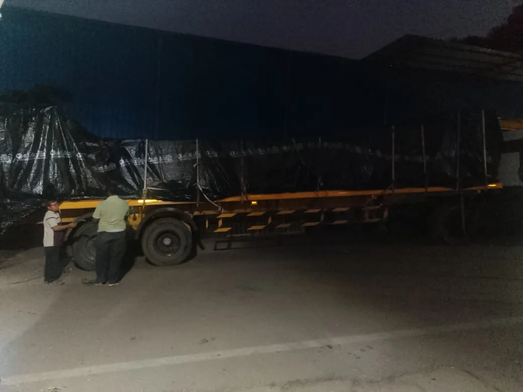 Crew securing a tarp over a load on a yellow trailer at night